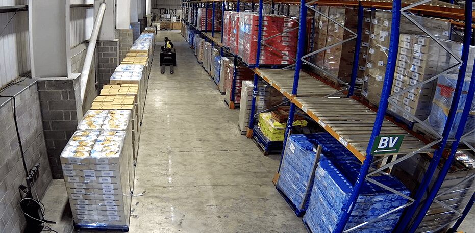 Guide to Warehouse Security Security camera view of warehouse interior with shelves and pallets.