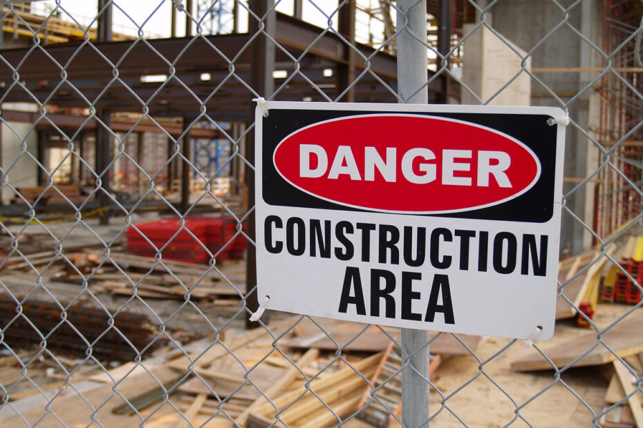 Construction site security sign reading danger construction area outside fenced construction site.