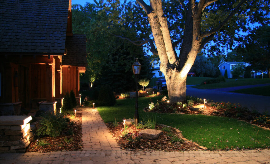 Spotlight-Floodlight Home Security Side view of the front of a house with spotlights and a floodlight on a tree.
