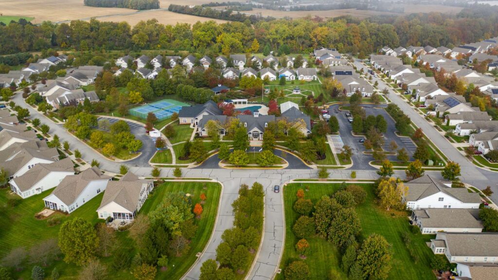 Aerial HOA community HOA community with homes, clubhouse, tennis courts and parking lots.